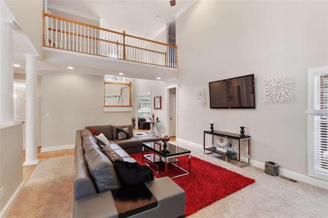 living room with decorative columns, light colored carpet, and a high ceiling