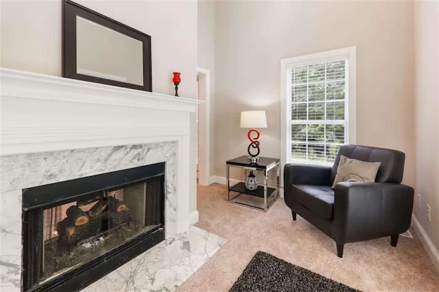 living area featuring a high end fireplace and light colored carpet