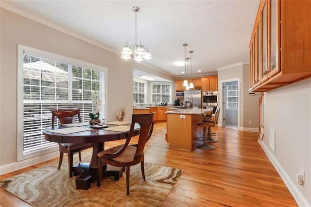 dining space with crown molding, light hardwood / wood-style flooring, and a chandelier