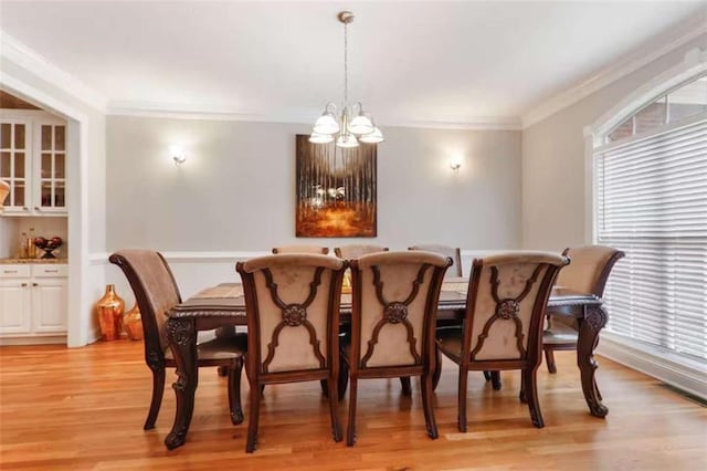 dining area featuring light wood-type flooring, crown molding, and a notable chandelier