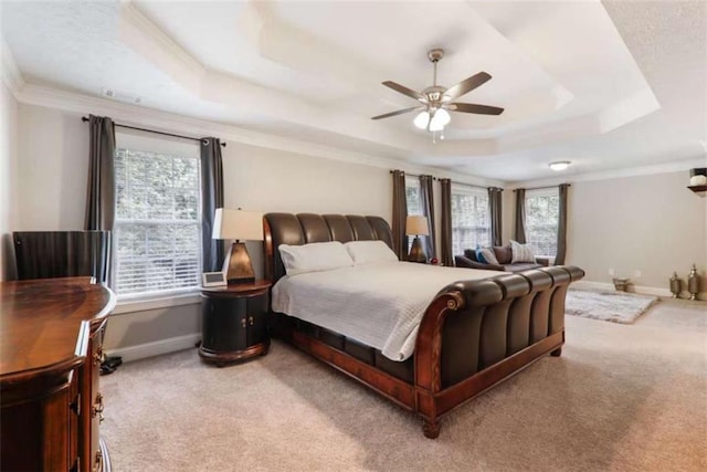 carpeted bedroom with a tray ceiling, ceiling fan, and crown molding