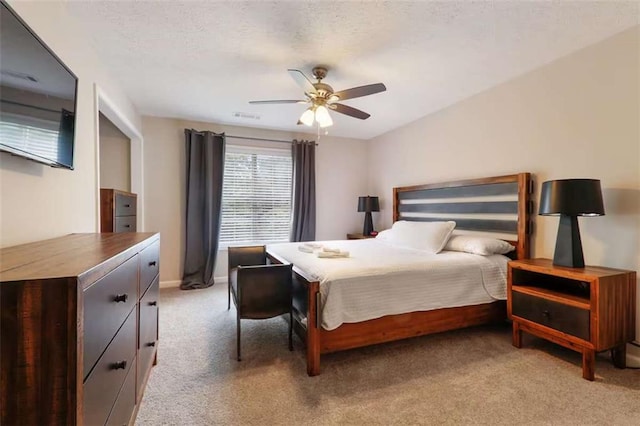 bedroom with light carpet, a textured ceiling, and ceiling fan