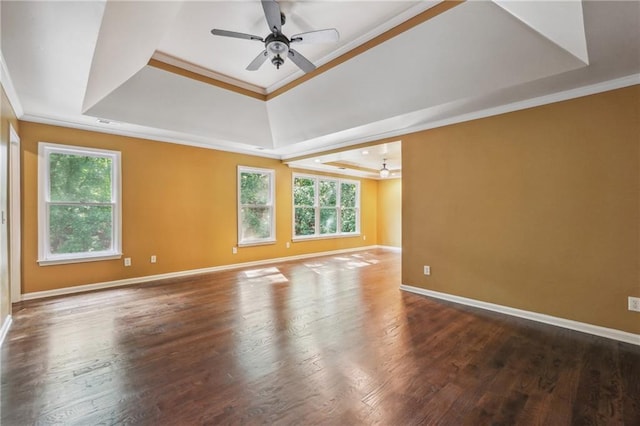 empty room featuring dark wood-type flooring, a wealth of natural light, a tray ceiling, crown molding, and ceiling fan