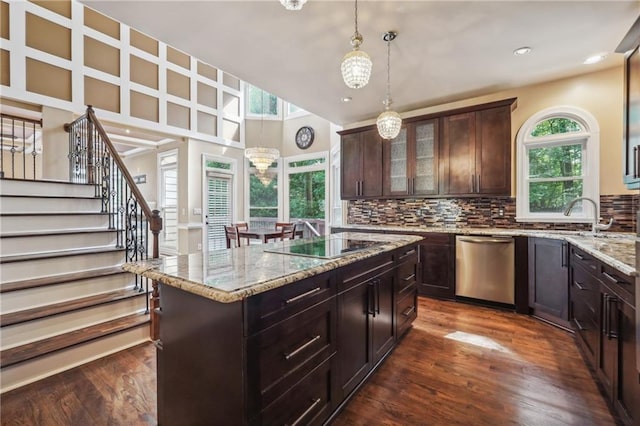 kitchen with a chandelier, black electric stovetop, a kitchen island, dark brown cabinetry, and stainless steel dishwasher