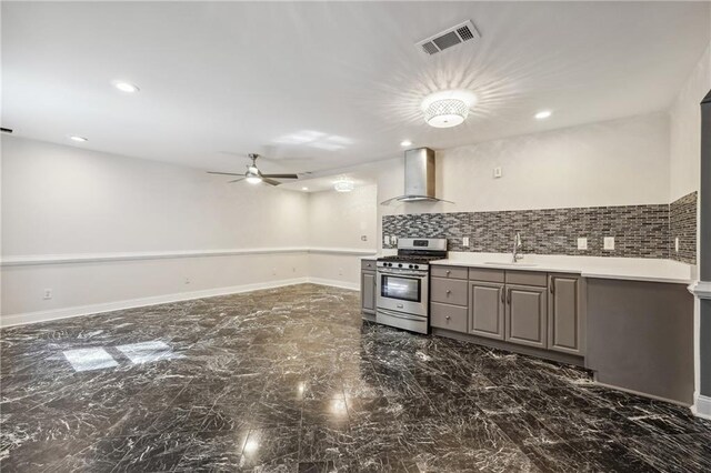 kitchen featuring gas stove, ceiling fan, wall chimney exhaust hood, sink, and backsplash