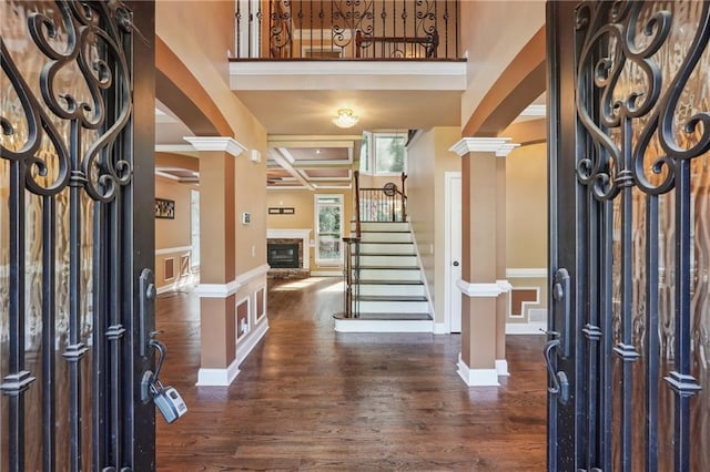 entryway featuring dark hardwood / wood-style flooring, beam ceiling, coffered ceiling, and ornate columns