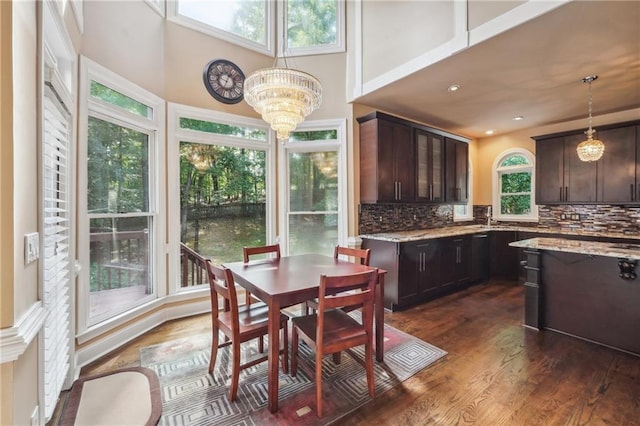 kitchen with an inviting chandelier, a healthy amount of sunlight, decorative backsplash, dark brown cabinetry, and decorative light fixtures