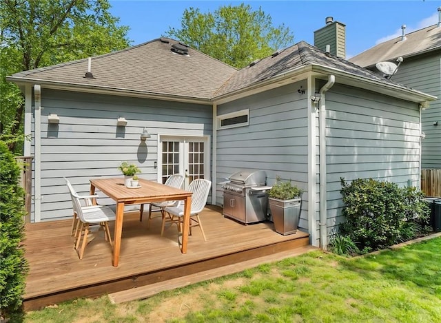 back of house with a wooden deck, french doors, a chimney, a shingled roof, and outdoor dining space