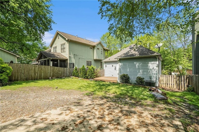 rear view of property featuring central AC unit, a yard, and fence