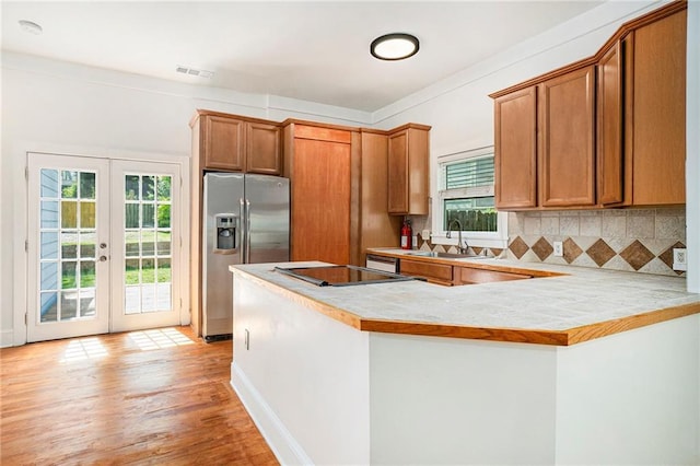 kitchen featuring tasteful backsplash, visible vents, stainless steel fridge, a sink, and light countertops