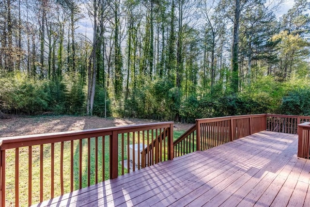 wooden deck with a view of trees and a yard