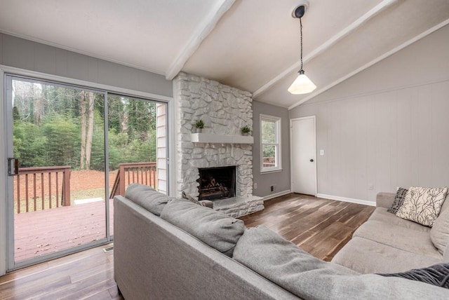 living room featuring vaulted ceiling with beams, a wealth of natural light, a fireplace, and wood-type flooring