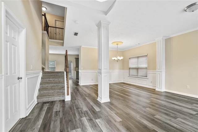 1212 Ashton Park Dr, Lawrenceville, GA 30045 - unfurnished living room featuring ornate columns, stairs, a chandelier, dark wood-type flooring, and wainscoting