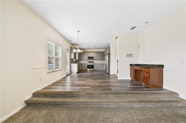 1212 Ashton Park Dr, Lawrenceville, GA 30045 - unfurnished living room with a chandelier, baseboards, dark wood-type flooring, and dark carpet