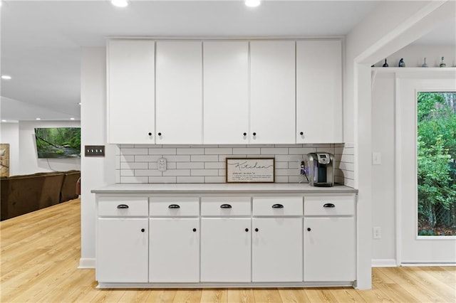 bar featuring white cabinetry, tasteful backsplash, and light hardwood / wood-style flooring