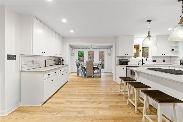 kitchen with pendant lighting, white cabinetry, decorative backsplash, light hardwood / wood-style floors, and stainless steel appliances