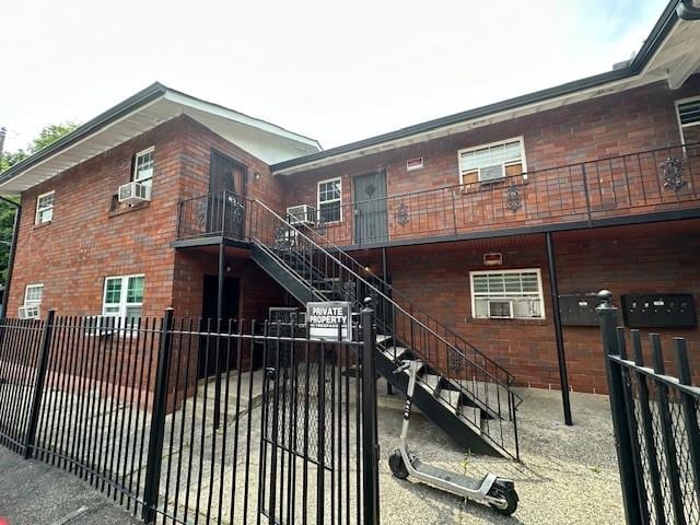 rear view of property featuring brick siding, cooling unit, stairs, and fence