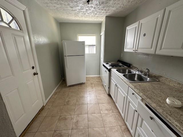 kitchen with a sink, white appliances, a textured ceiling, and white cabinetry