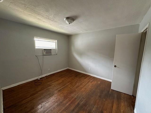 spare room featuring cooling unit, baseboards, a textured ceiling, and wood finished floors