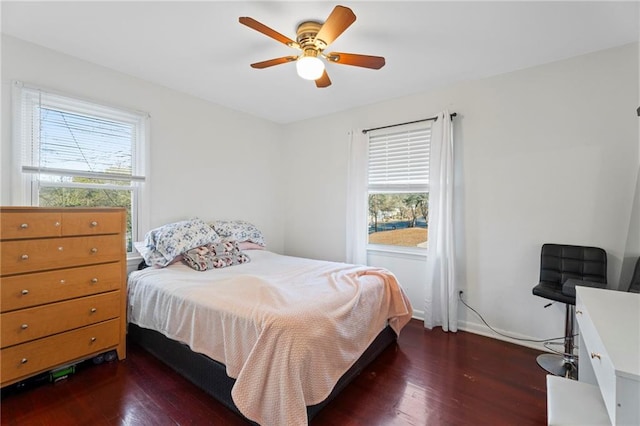 bedroom with multiple windows, ceiling fan, and dark hardwood / wood-style flooring