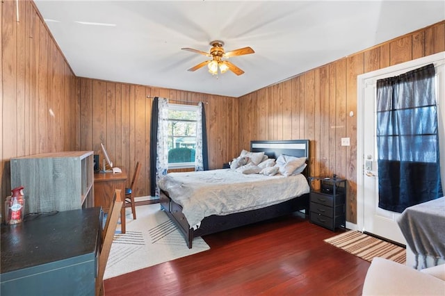 bedroom featuring dark hardwood / wood-style flooring, wooden walls, and ceiling fan