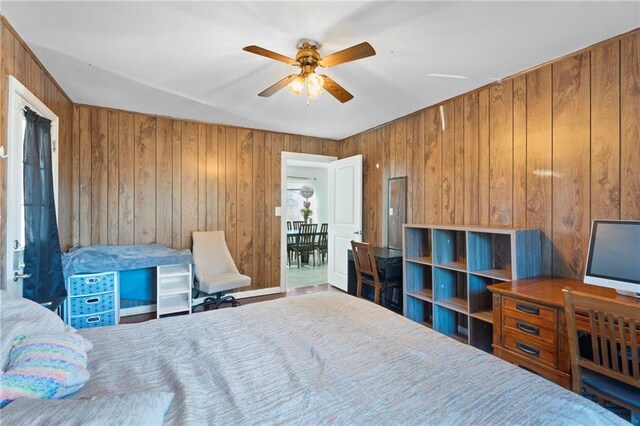 bedroom with ceiling fan and wood walls