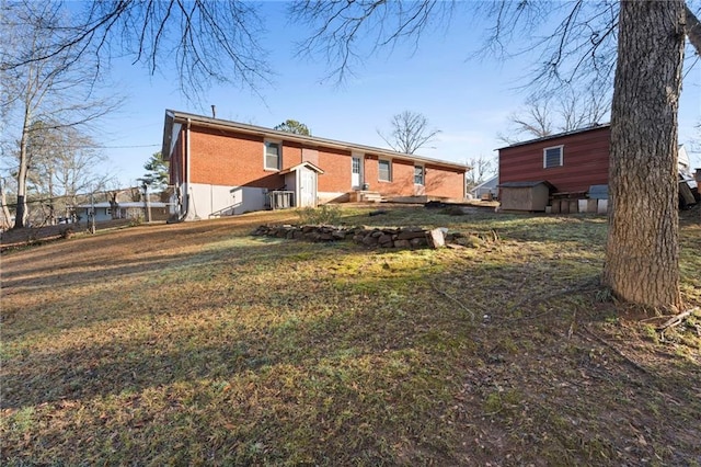 rear view of property featuring brick siding and a yard