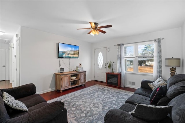 living area featuring visible vents, ceiling fan, baseboards, and wood finished floors