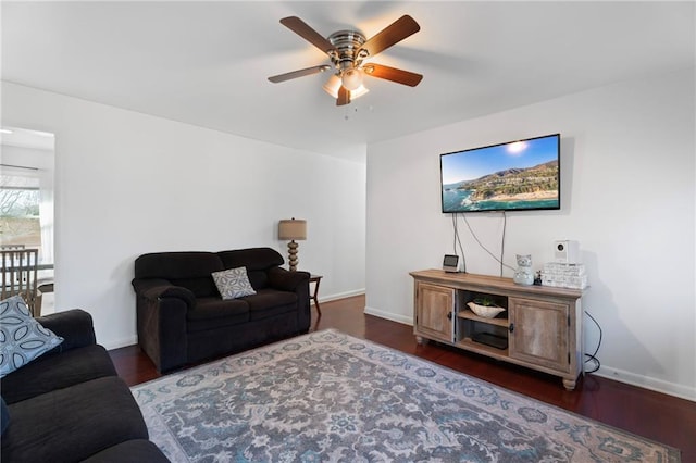 living room with ceiling fan, baseboards, and wood finished floors