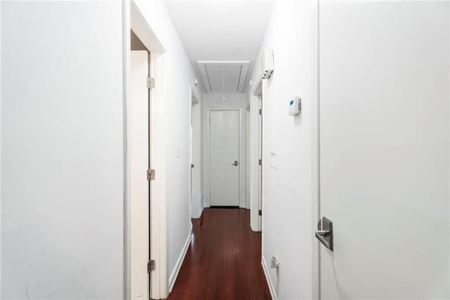 hallway featuring attic access, baseboards, and wood finished floors