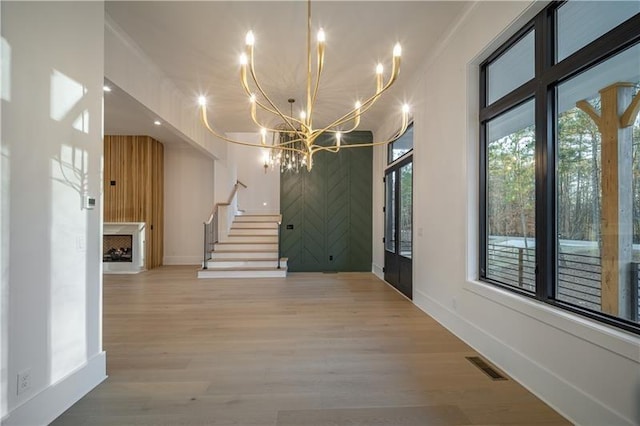 interior space featuring stairs, light wood-style flooring, visible vents, and a chandelier