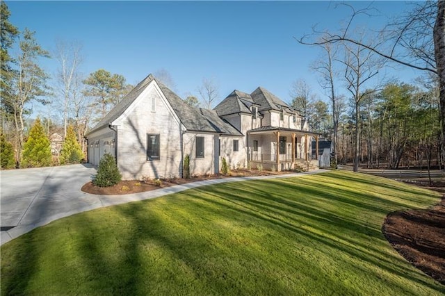 french provincial home featuring a front lawn, an attached garage, driveway, and a porch