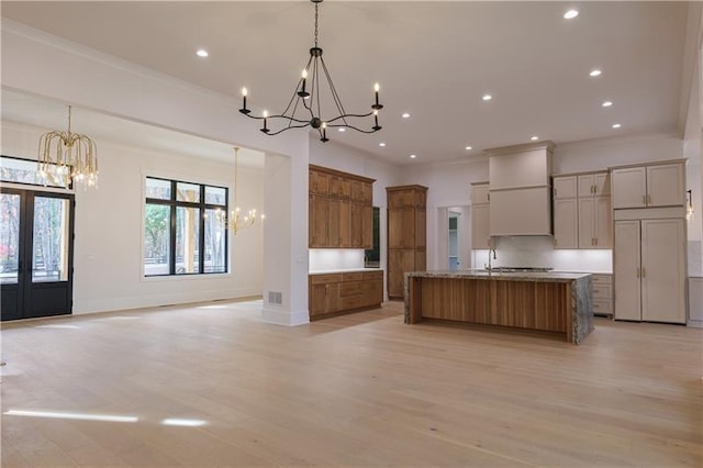 kitchen with a chandelier, recessed lighting, premium range hood, and brown cabinetry
