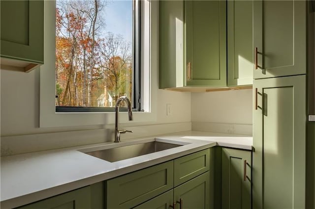 kitchen with green cabinetry, light countertops, and a sink
