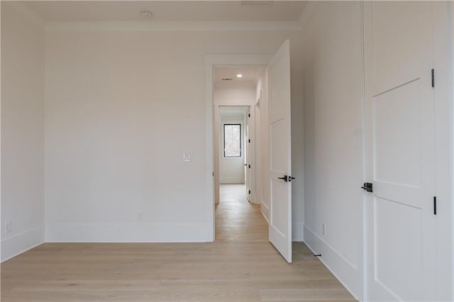 hallway featuring crown molding, baseboards, and light wood finished floors