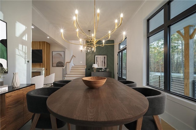 dining space featuring ornamental molding, stairs, and a notable chandelier