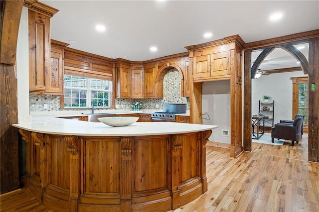 kitchen featuring light countertops, tasteful backsplash, a peninsula, light wood finished floors, and recessed lighting