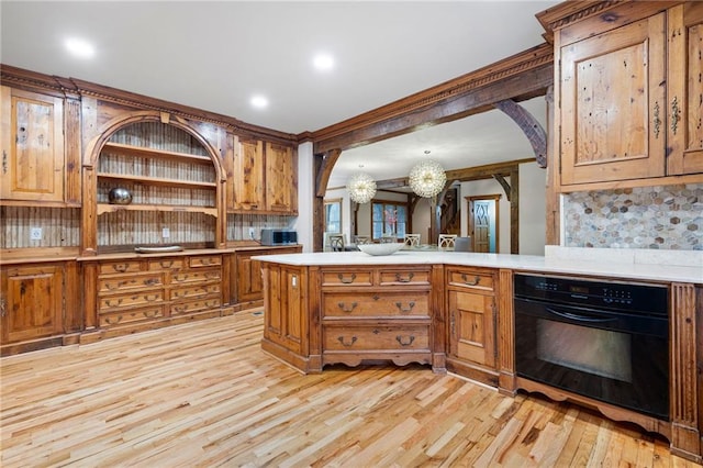 kitchen with oven, a chandelier, light wood-style floors, light countertops, and stainless steel microwave