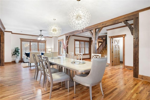 dining area featuring a chandelier, crown molding, baseboards, light wood-style flooring, and stairs