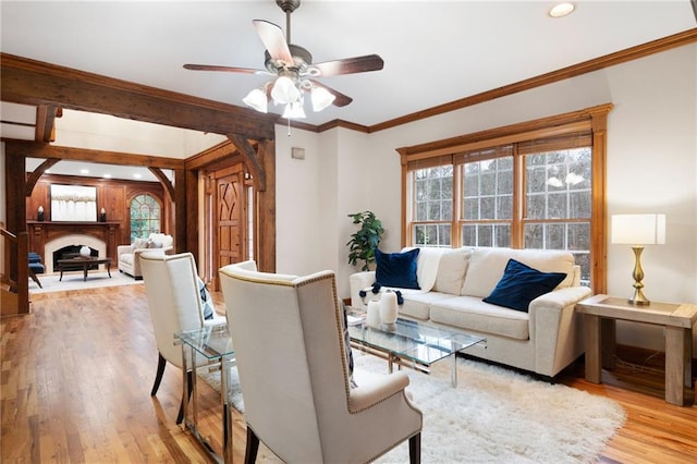 living area featuring light wood finished floors, a ceiling fan, a fireplace, crown molding, and recessed lighting