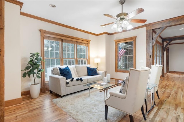 living room with light wood-style flooring, baseboards, crown molding, and a ceiling fan