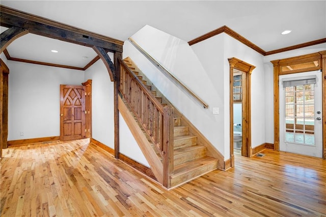 stairs featuring arched walkways, crown molding, hardwood / wood-style floors, baseboards, and recessed lighting