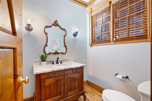 bathroom featuring toilet, wood finished floors, vanity, and baseboards