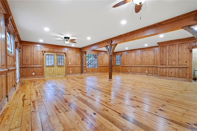 unfurnished living room featuring a ceiling fan, light wood-type flooring, wooden walls, crown molding, and recessed lighting