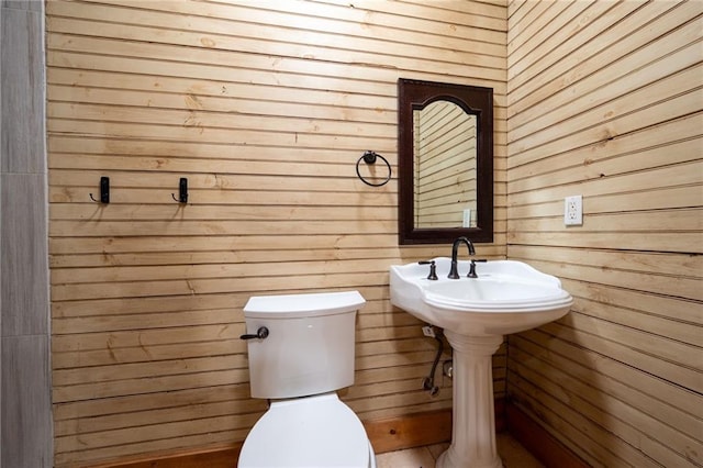 half bathroom with wood walls and toilet