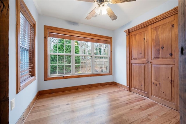 unfurnished bedroom with light wood finished floors, baseboards, and a ceiling fan