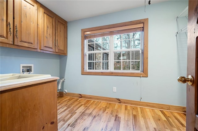 clothes washing area featuring cabinet space, washer hookup, baseboards, and wood finished floors