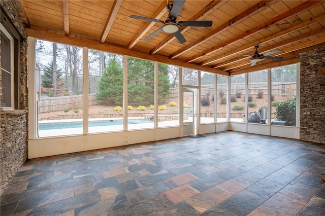 unfurnished sunroom with ceiling fan, beamed ceiling, and healthy amount of natural light
