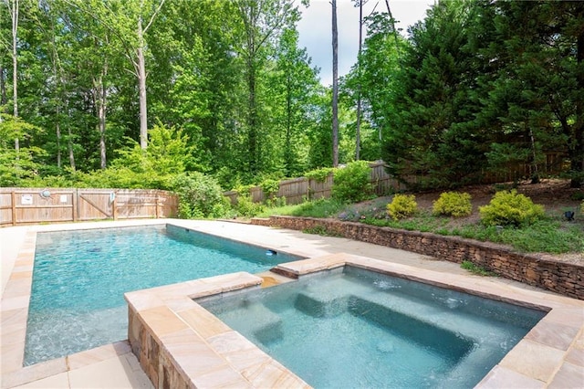 view of pool with a fenced backyard and a pool with connected hot tub