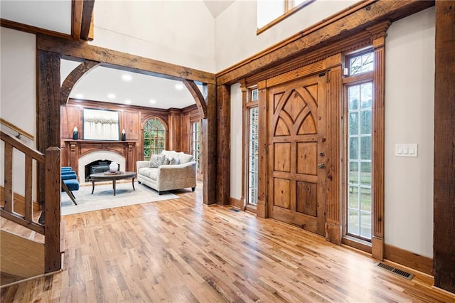 entrance foyer featuring arched walkways, plenty of natural light, a high ceiling, wood finished floors, and baseboards
